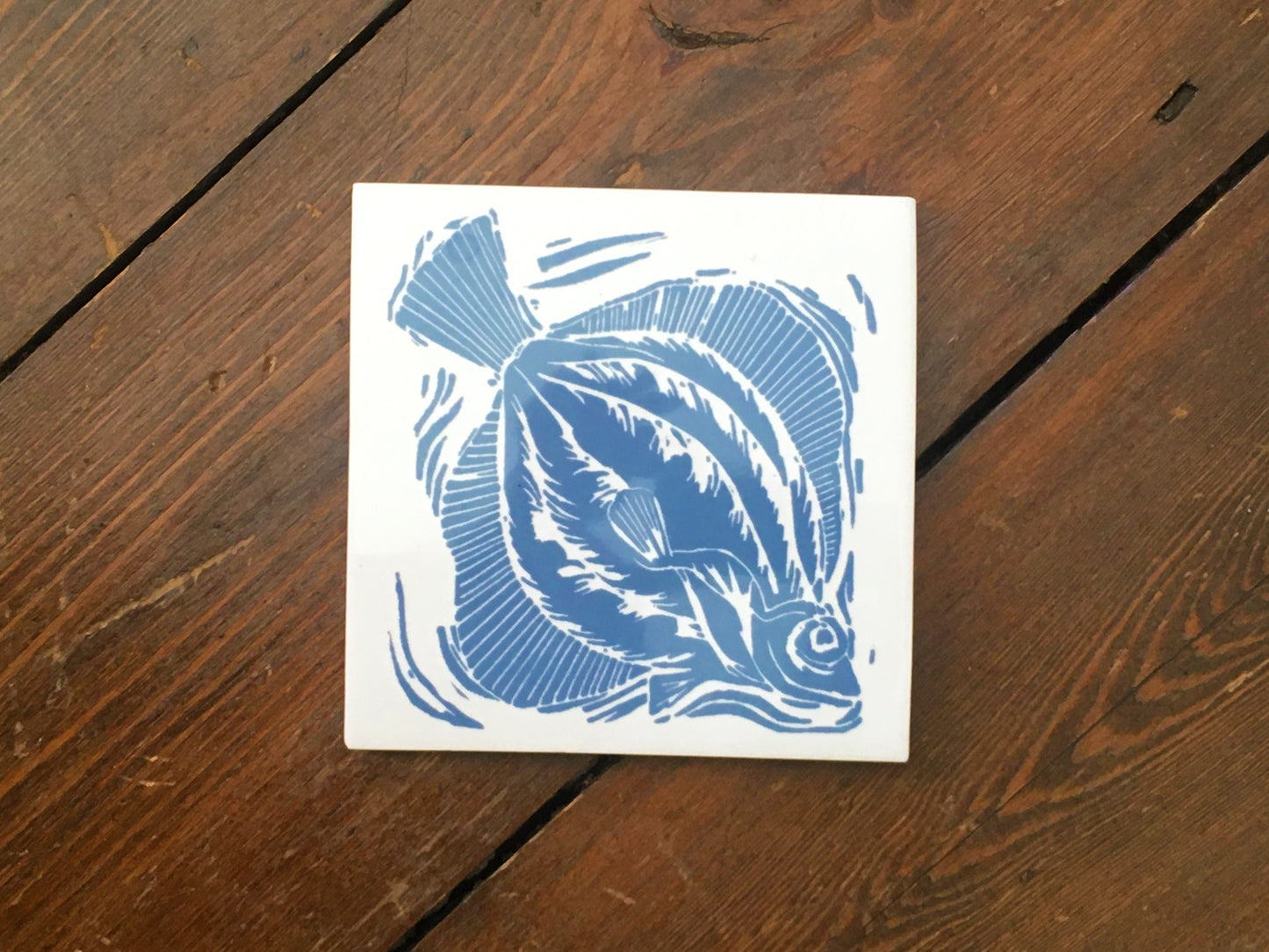 Plaice handmade tile trivet lino cut by Kate Guy in dark blue