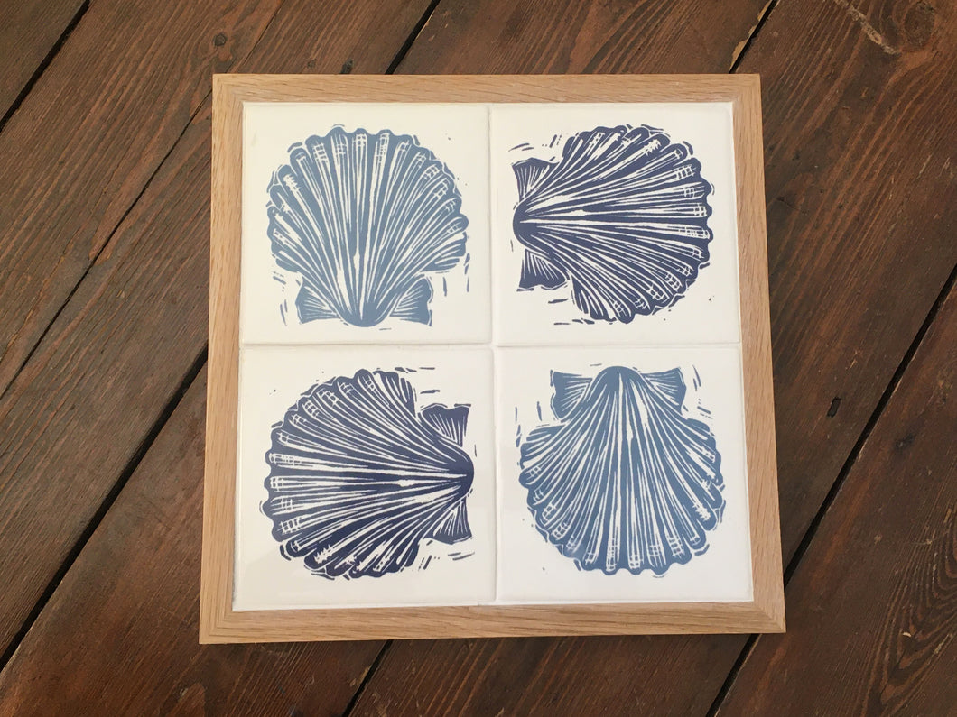 Scallop Shell Handmade tile trivet, table centrepiece. Linocut print of scallop shells in pale and dark blue on four tiles framed in English oak